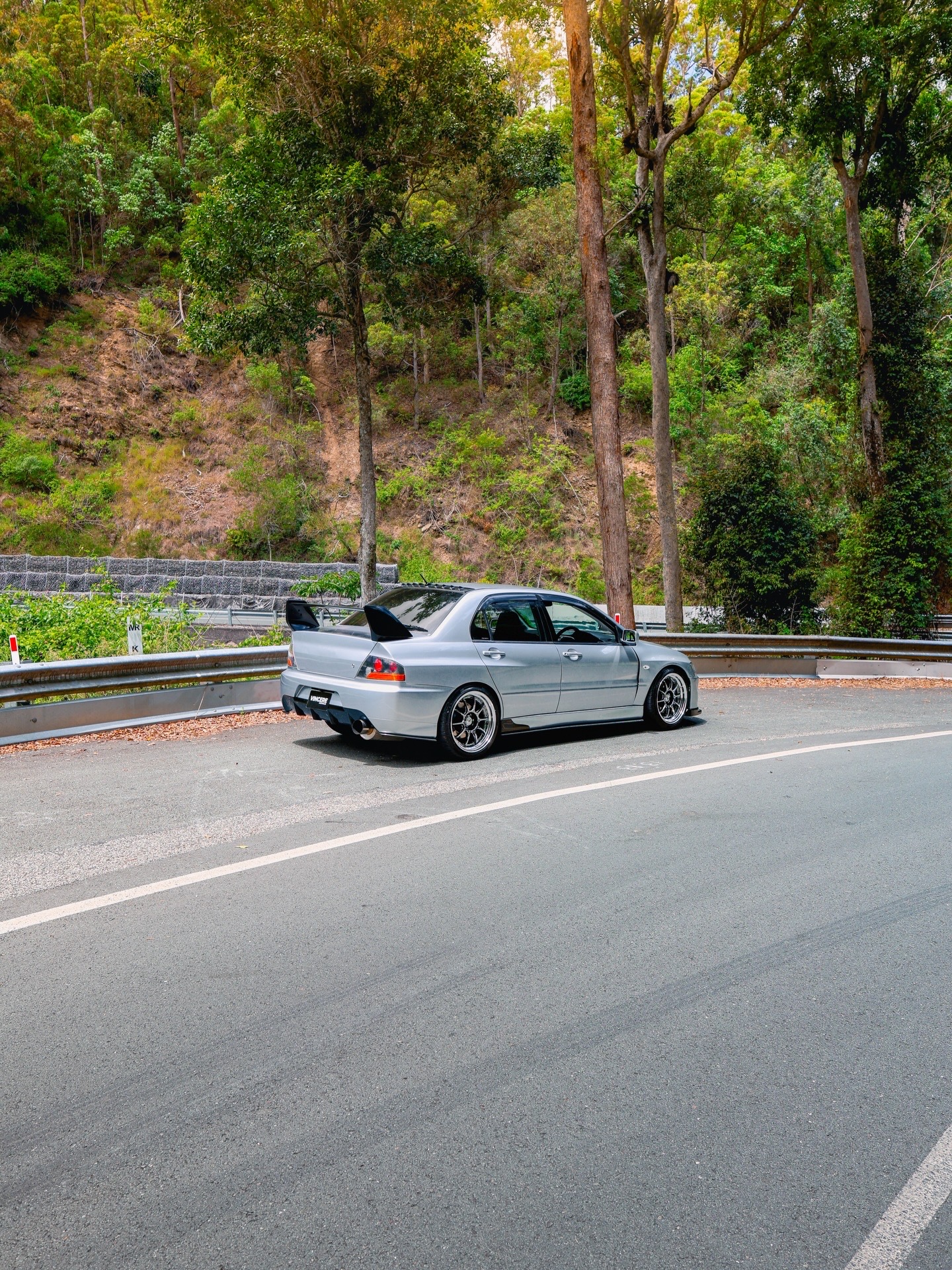 Silver Mitsubishi Evo parked on a forest mountain road