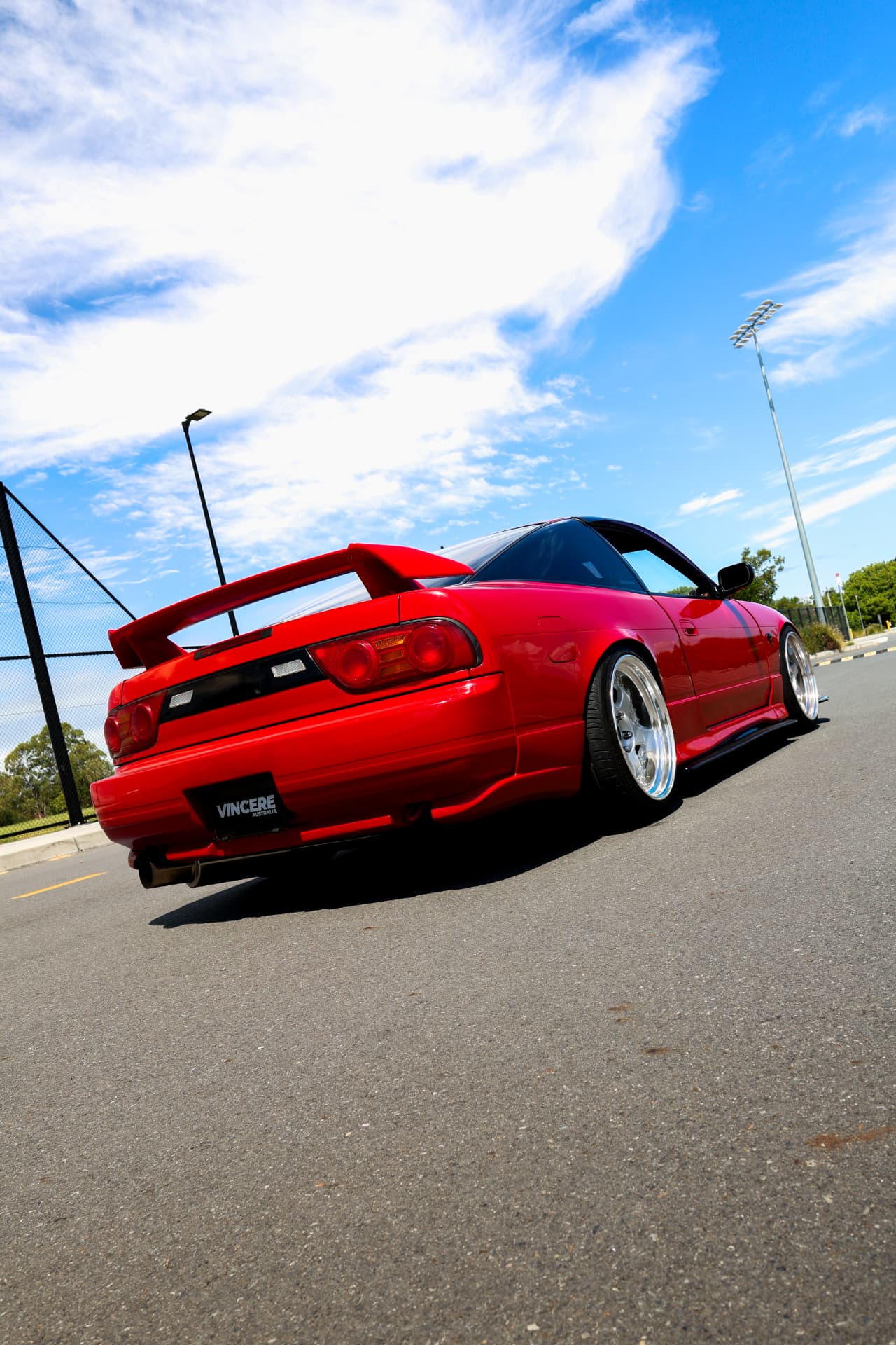 Red Nissan 180SX rear three-quarter under a blue sky
