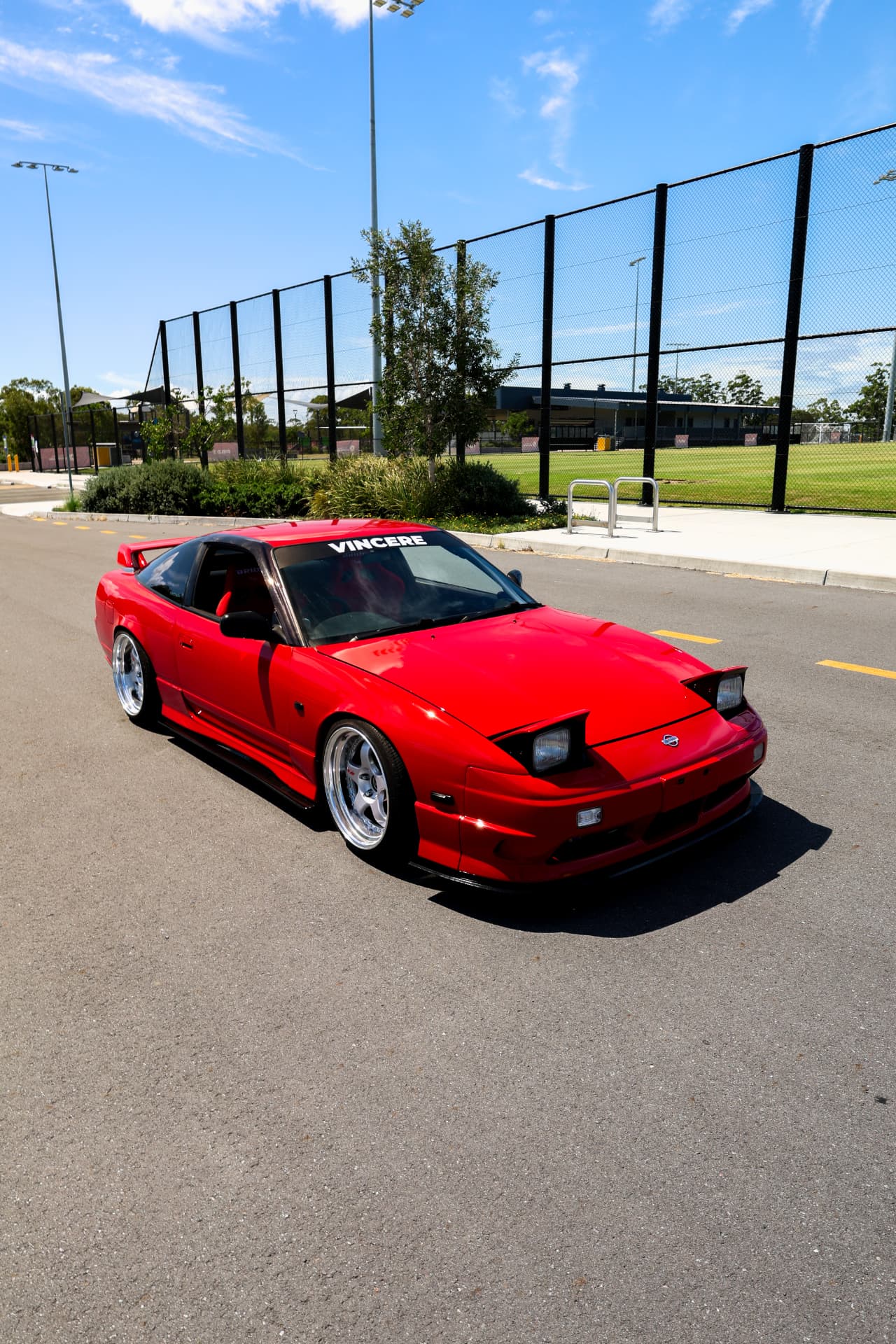 Red Nissan 180SX with pop-up headlights on open asphalt