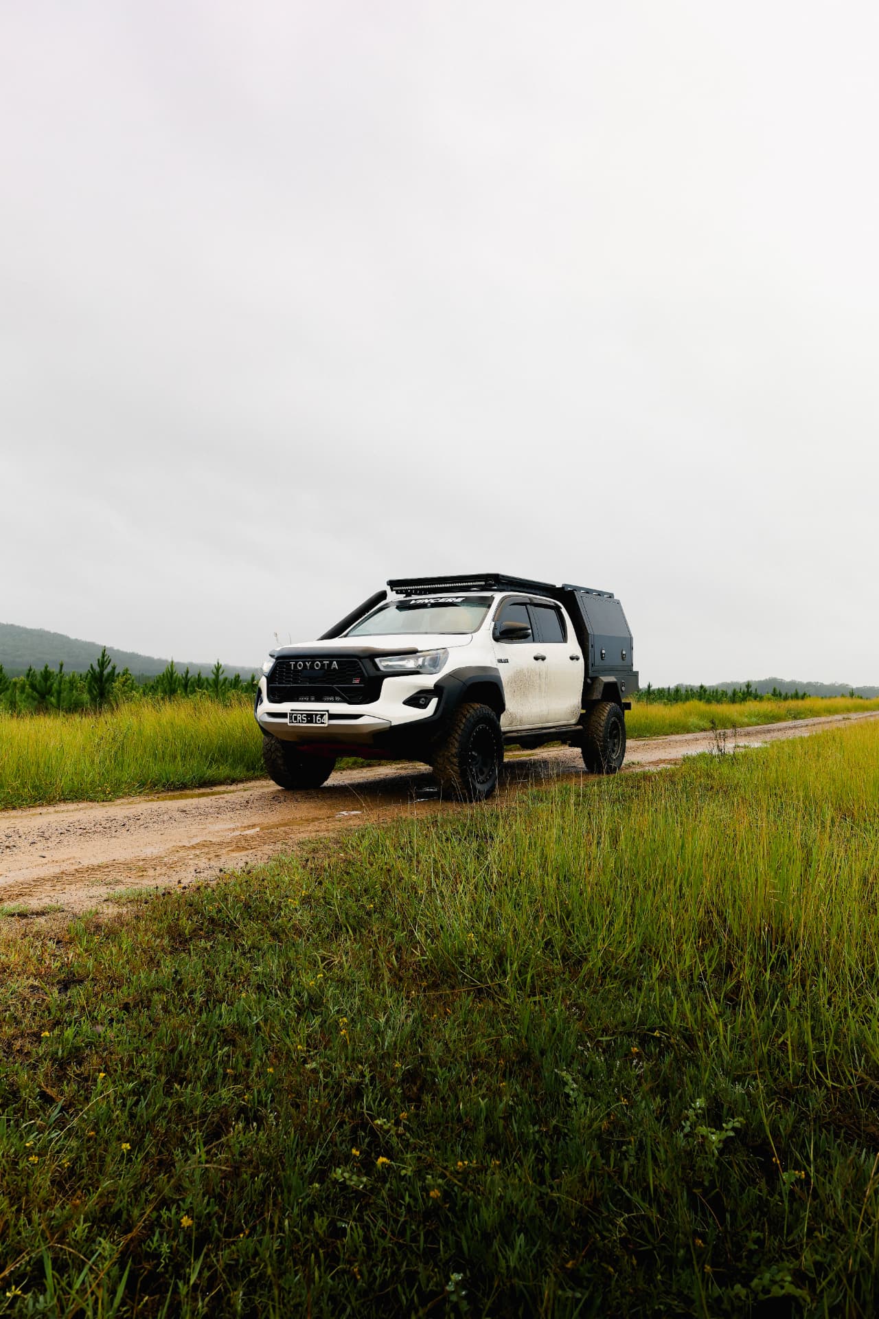 Toyota HiLux touring rig on a wet dirt track