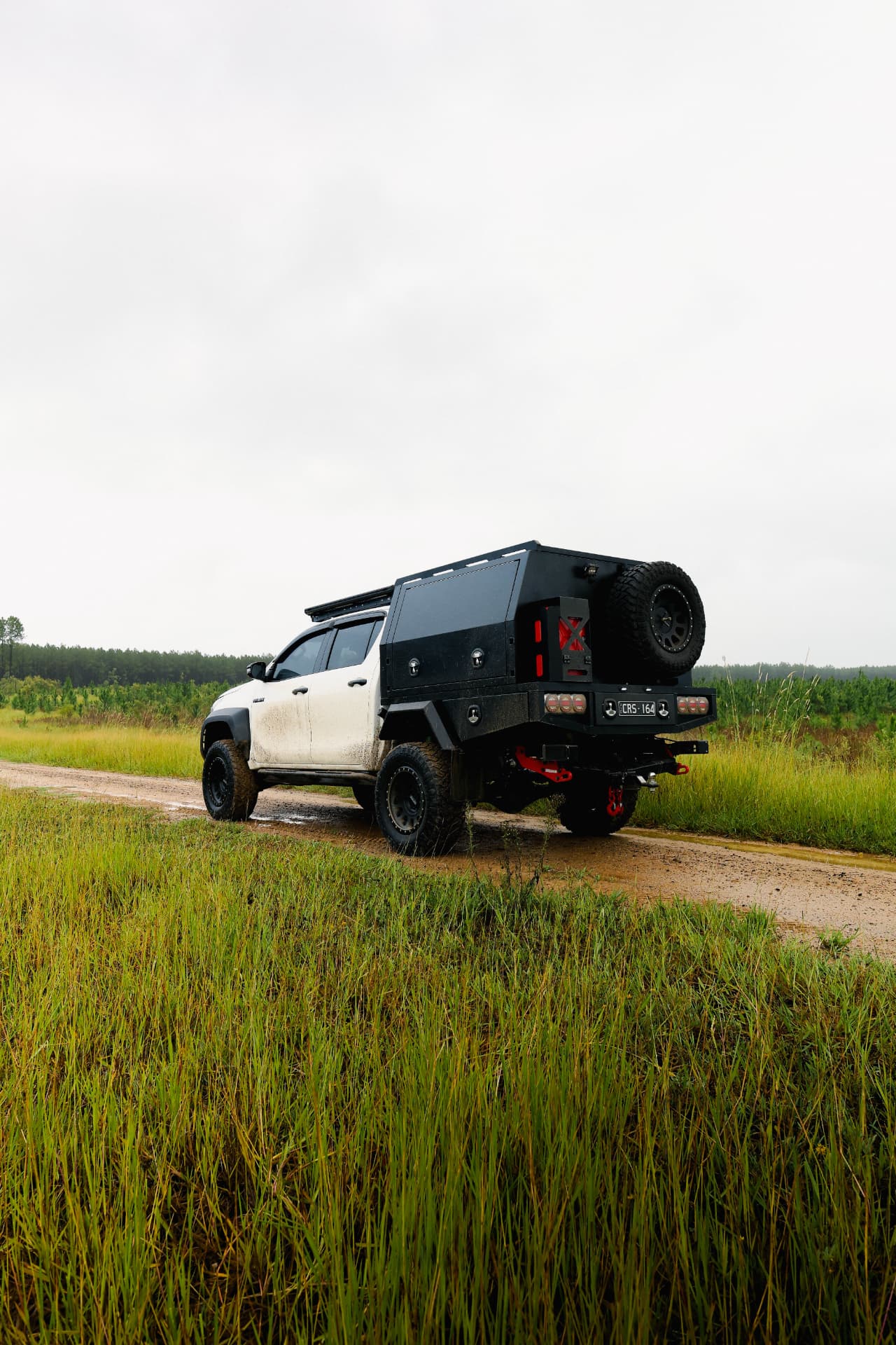 Rear of a HiLux with canopy and spare wheel on a bush track