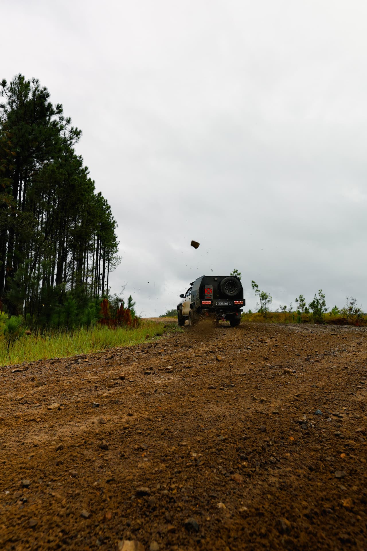 HiLux cresting a dirt rise, stone flying behind