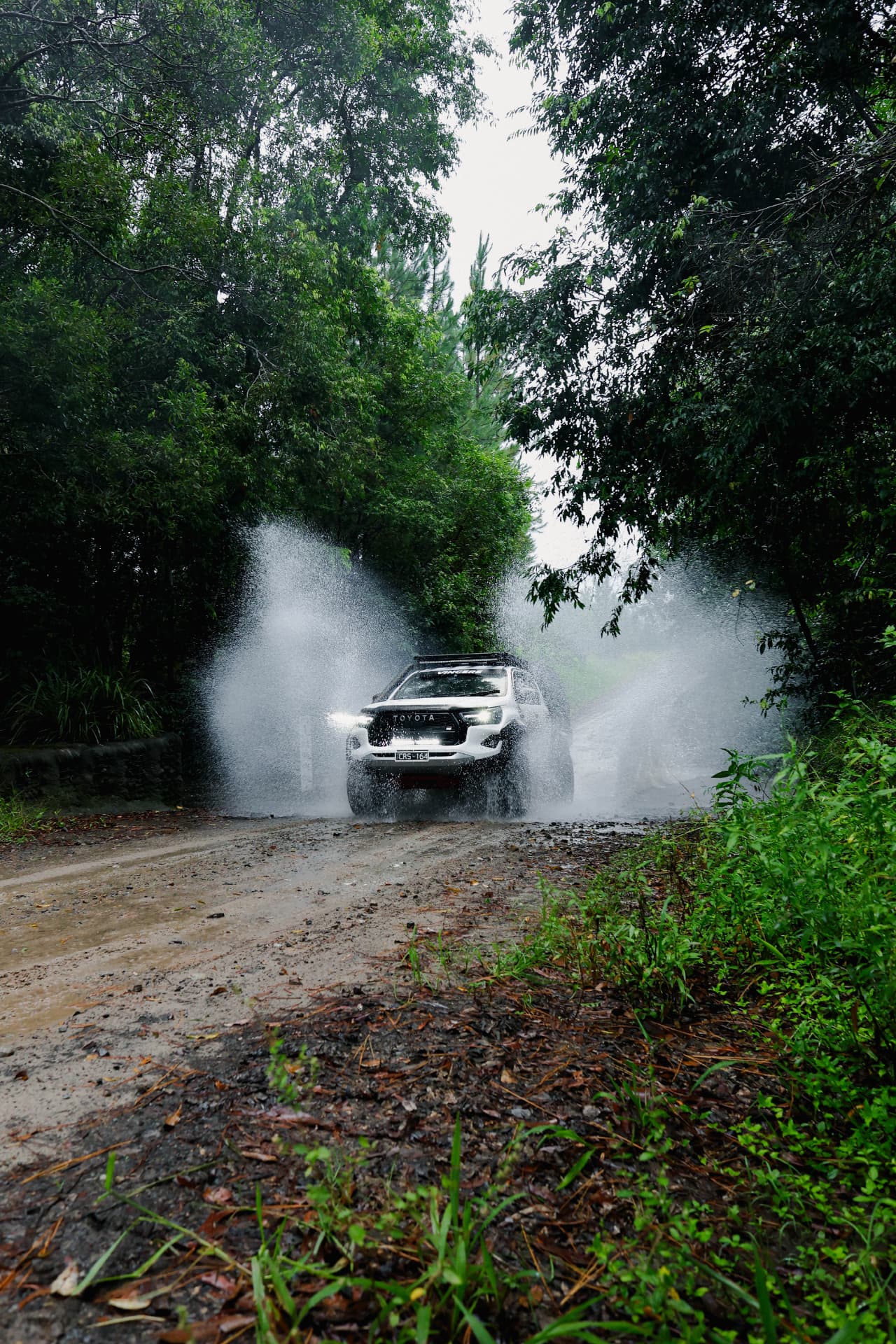 HiLux blasting through a rainforest water crossing