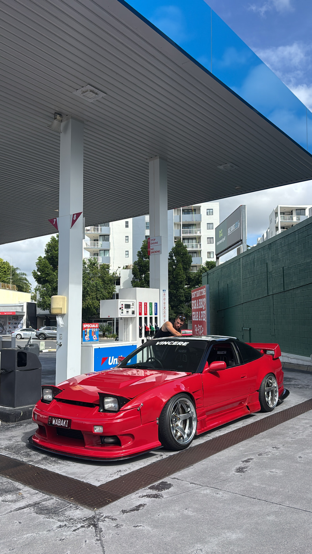 Red Nissan 180SX refuelling at a service station