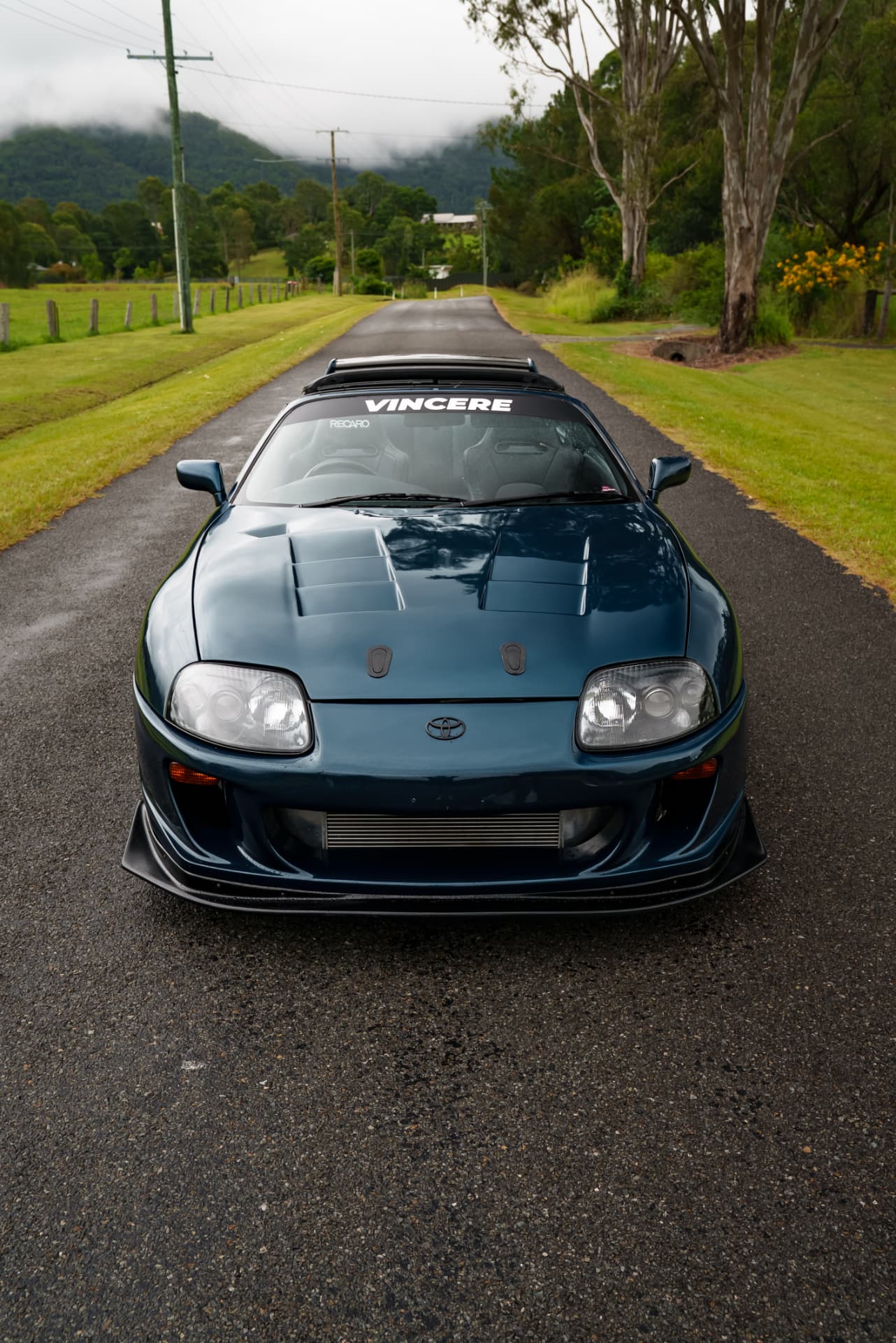 Head-on view of a teal Toyota Supra on a country lane