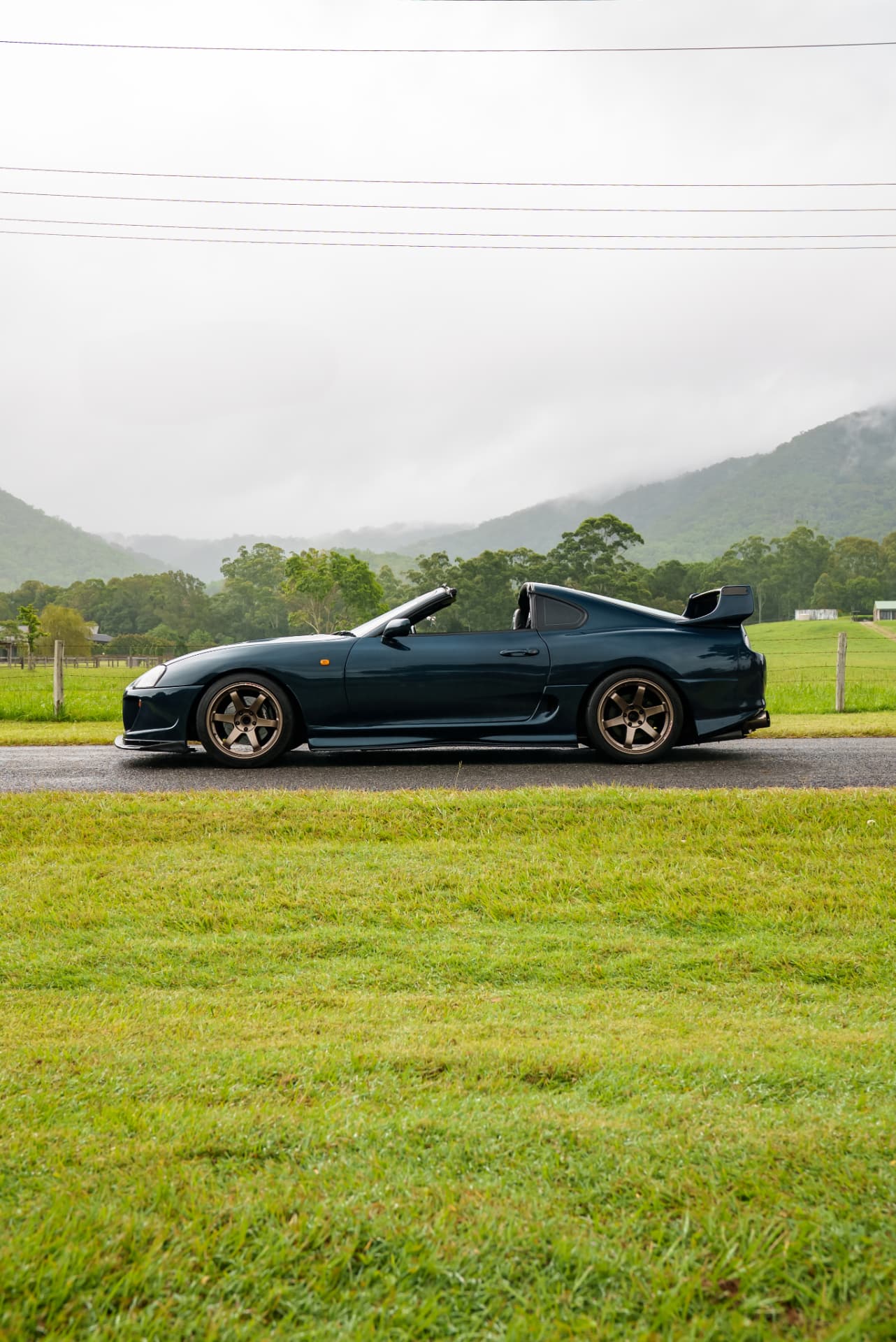 Teal Supra side profile against misted hills