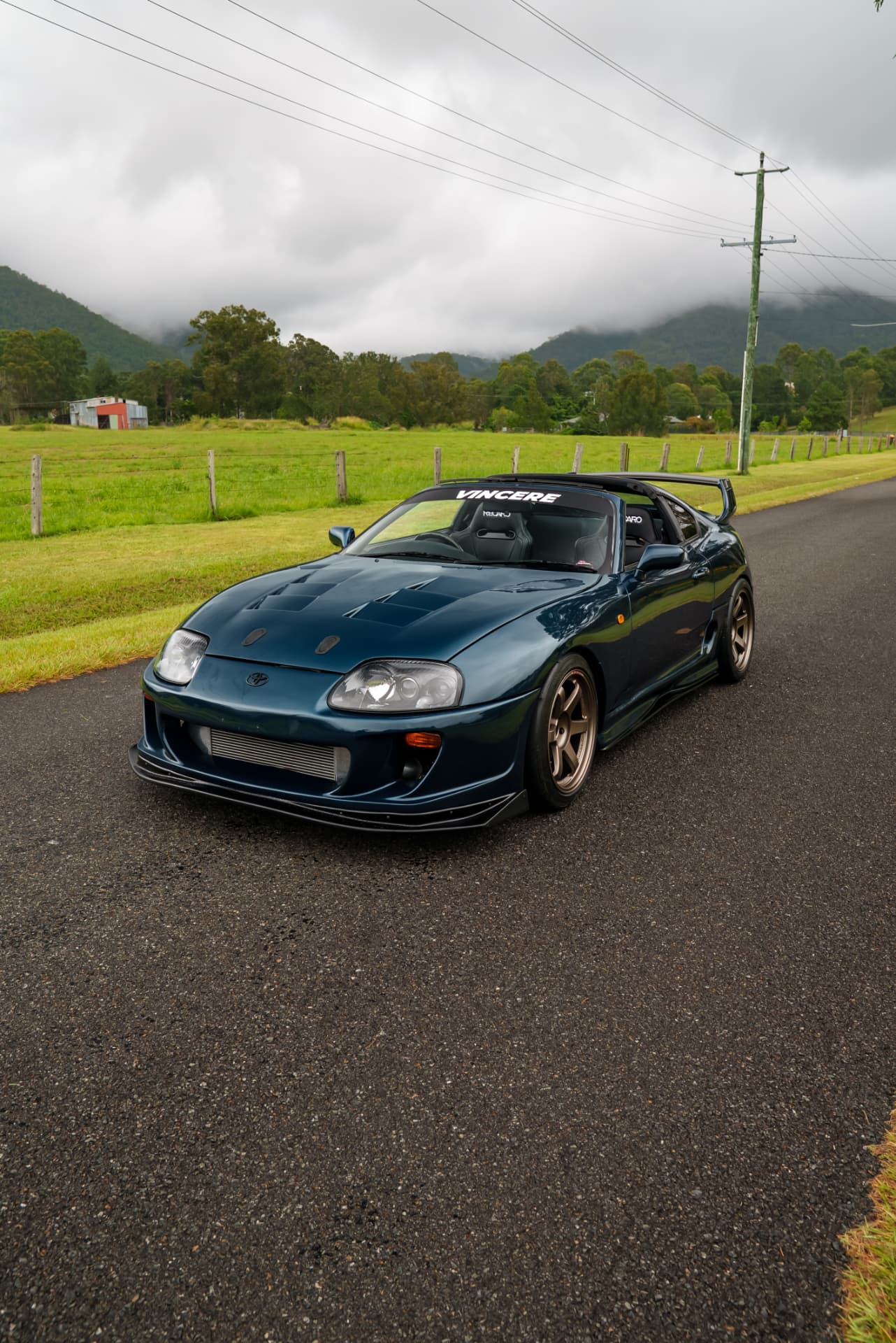Teal Supra with targa top removed on a rural road