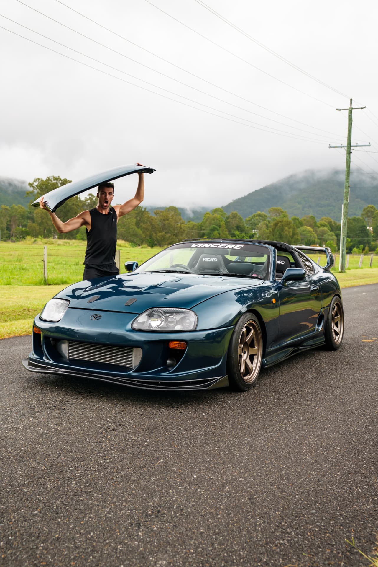 Owner lifting the targa roof off a teal Supra