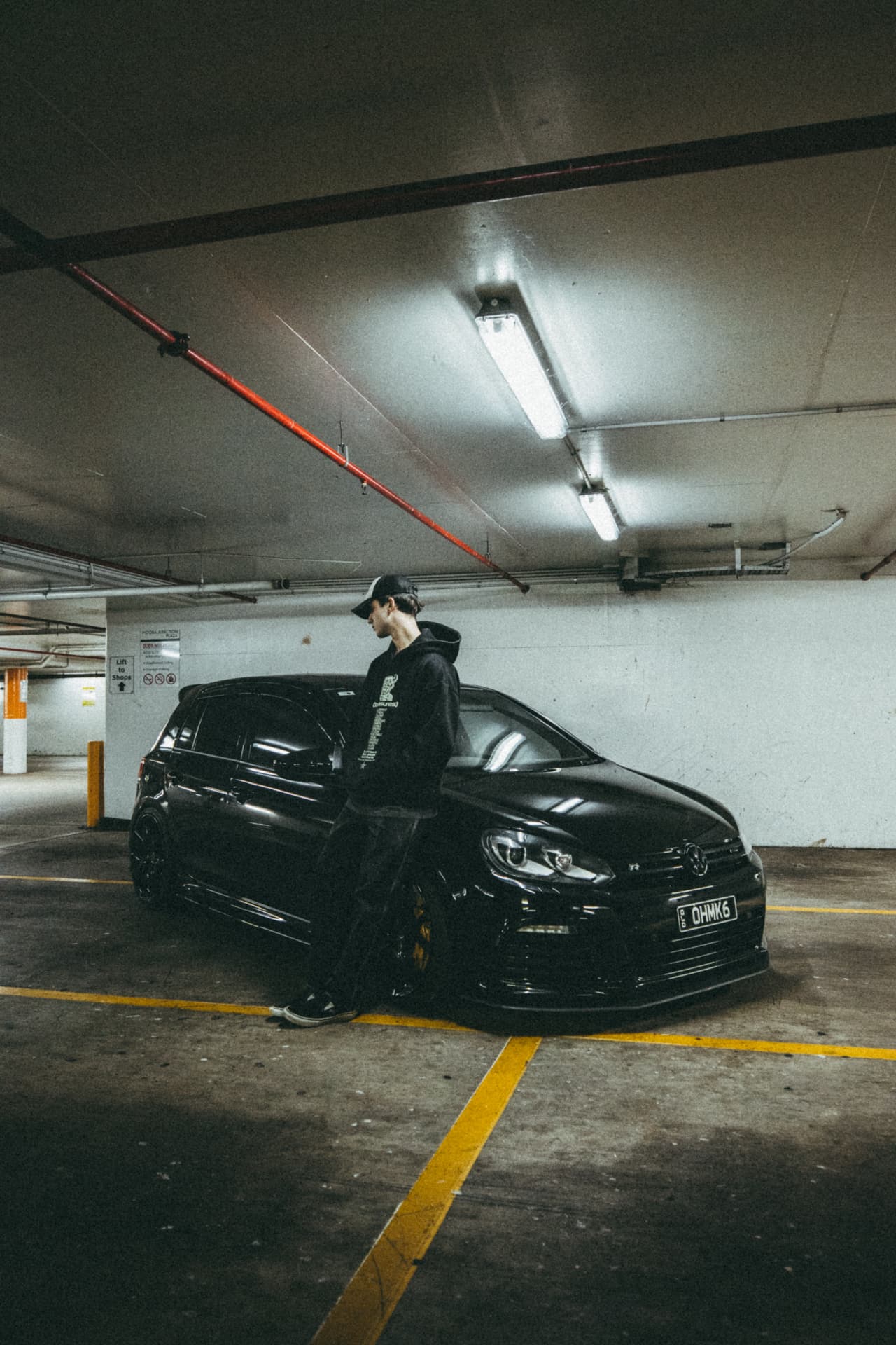 Black Golf R in a carpark with the owner leaning against it