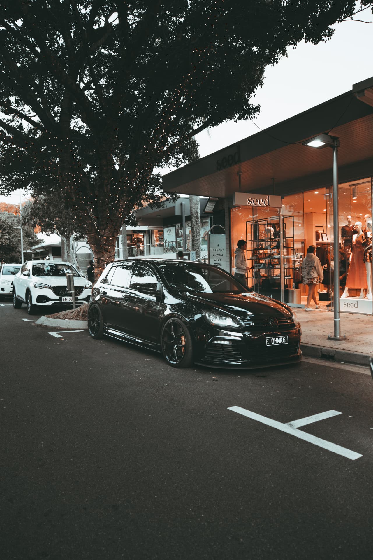 Black Golf R parked on a shopfront street at dusk