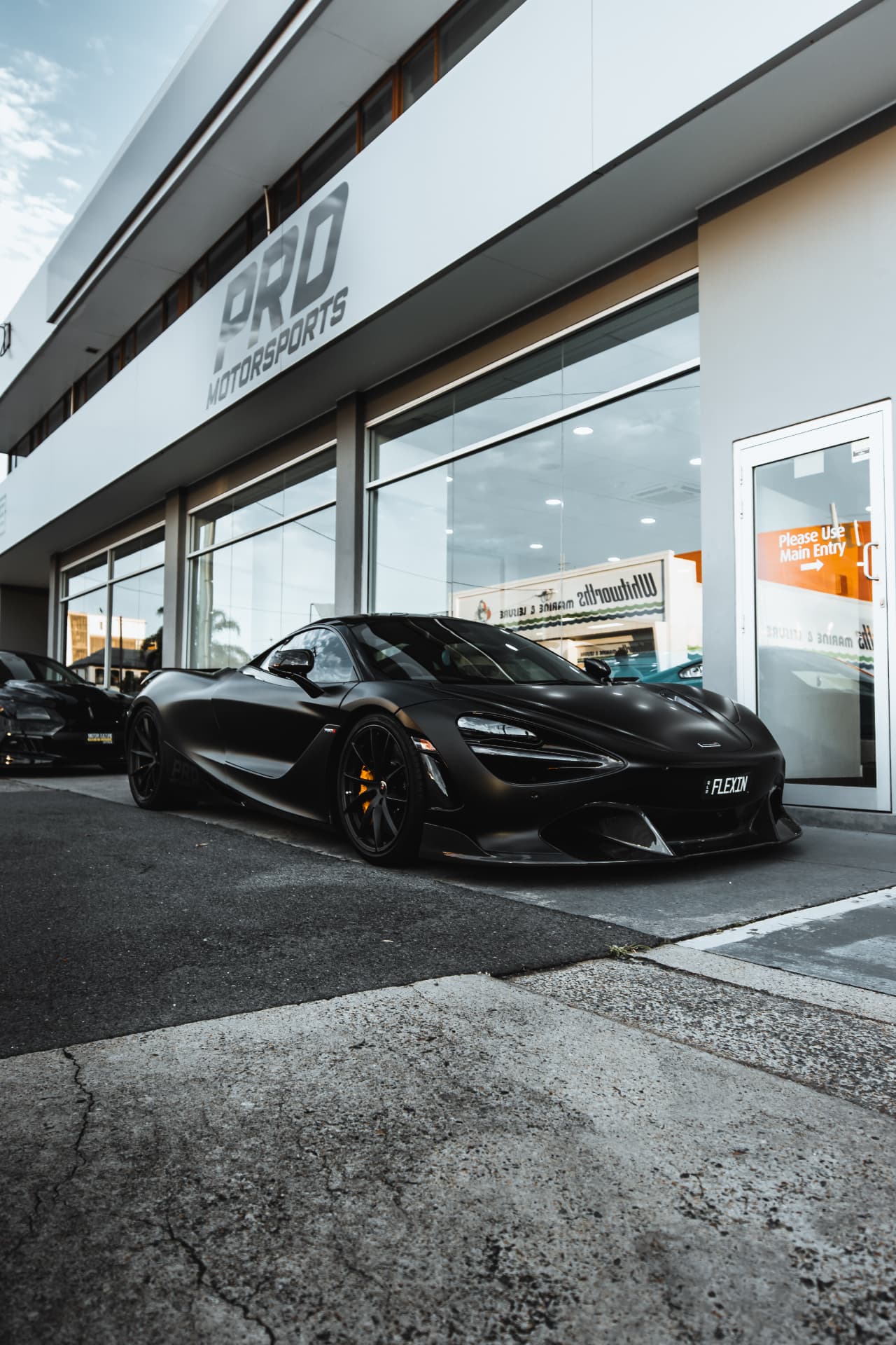 Satin black McLaren 720S outside a motorsports showroom