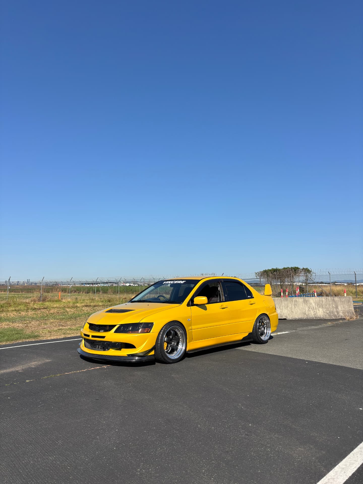 Yellow Mitsubishi Evo VIII on open tarmac
