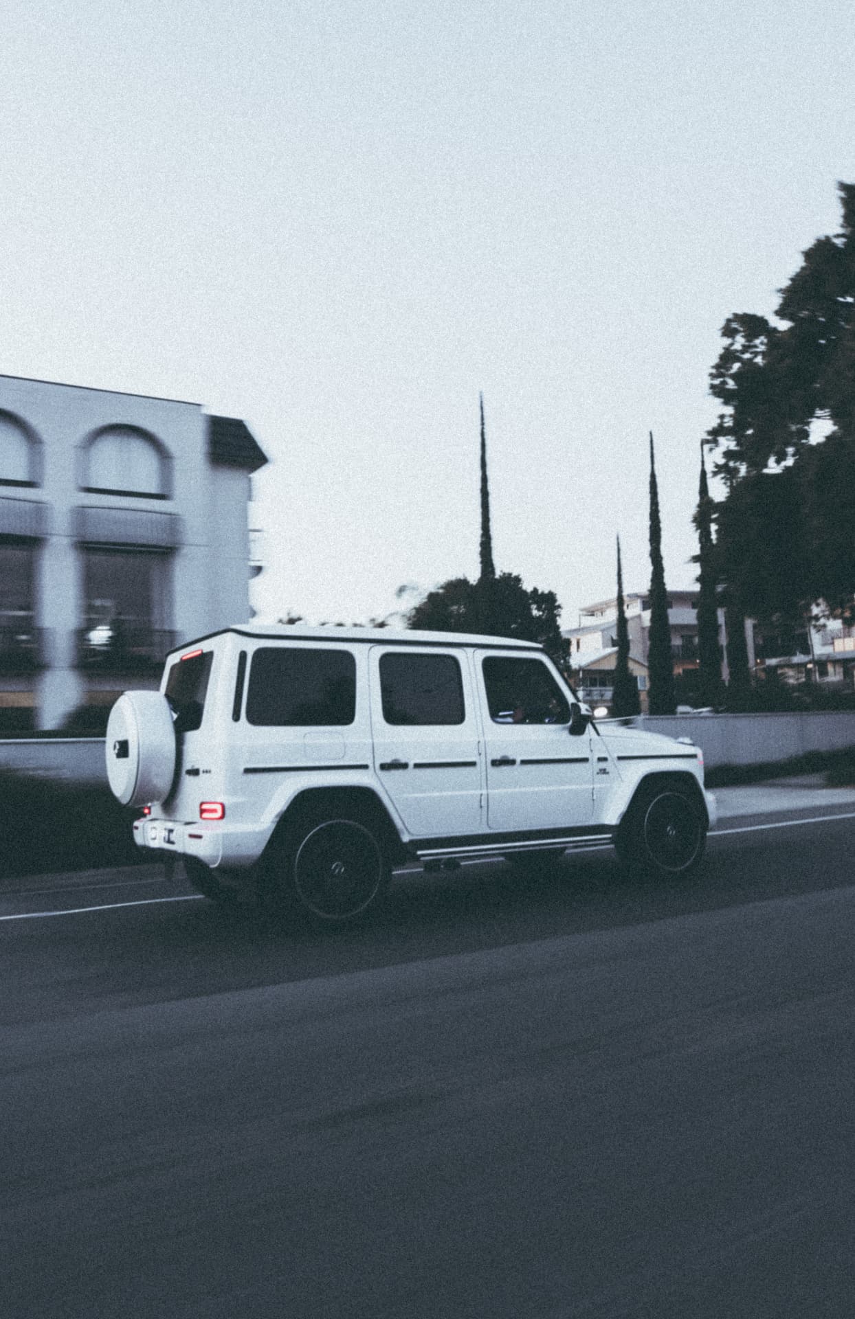White Mercedes-AMG G63 rolling shot at dusk