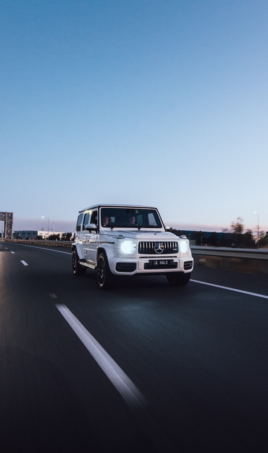 White G63 head-on with headlights lit on the highway