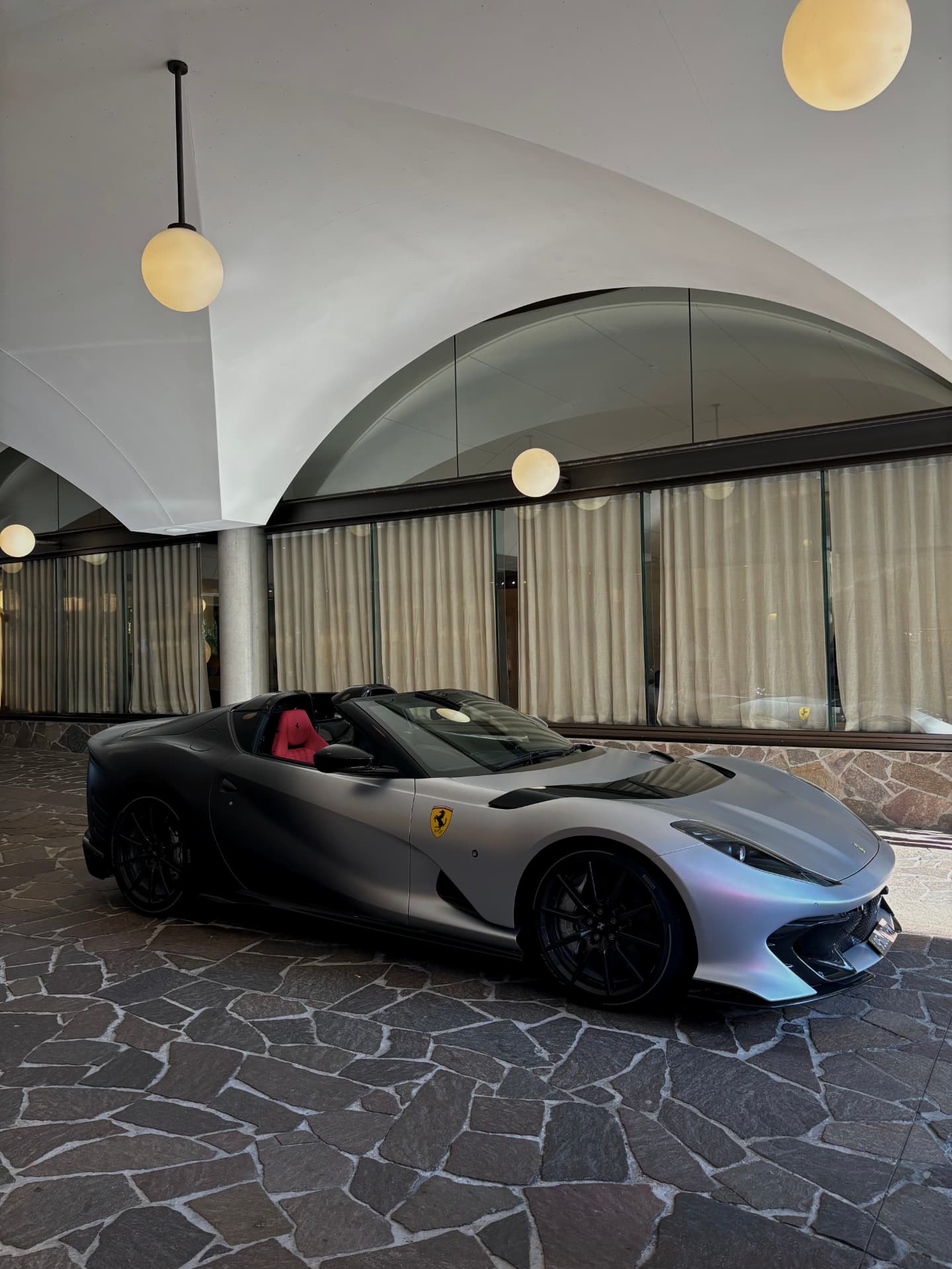 Silver Ferrari 812 GTS parked under a vaulted hotel portico