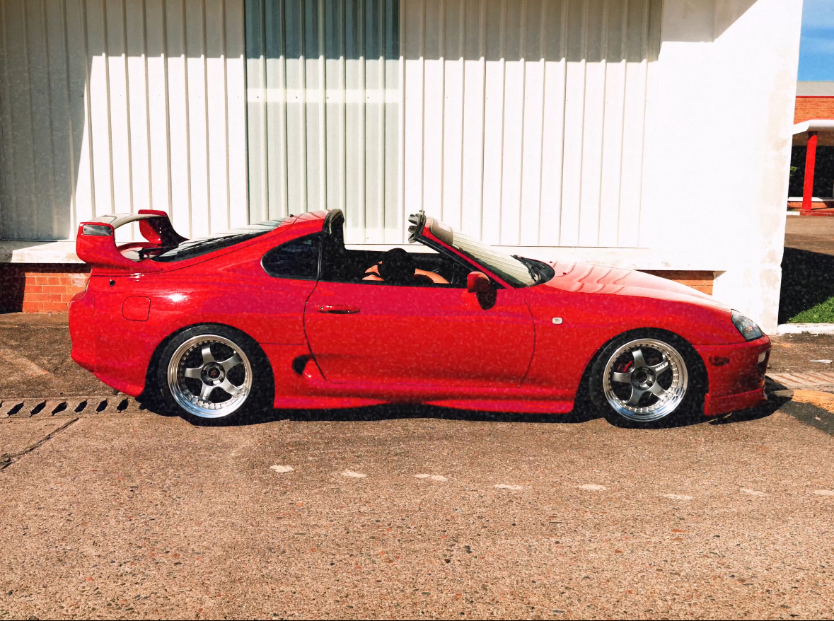 Red Toyota Supra side profile with targa top removed