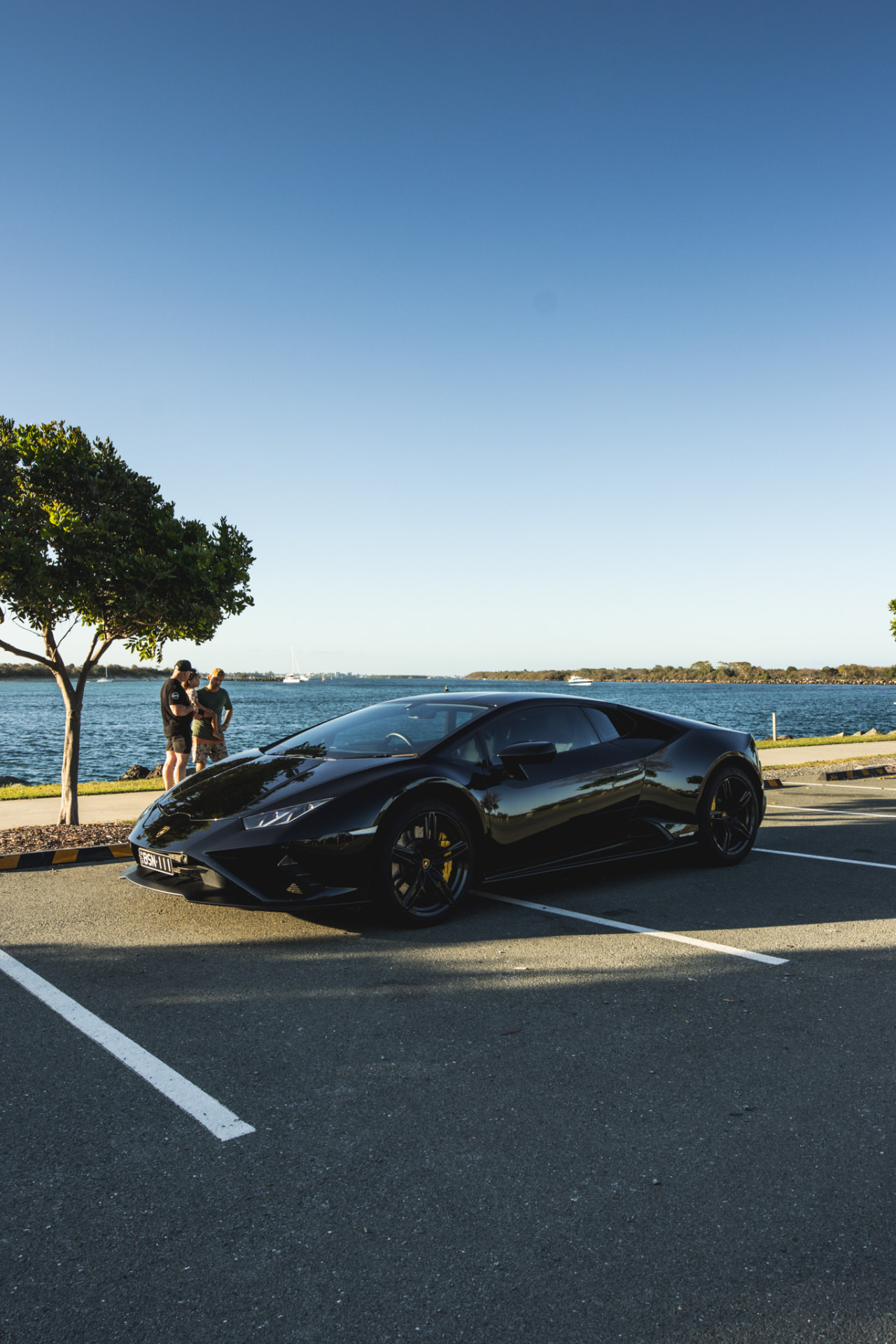Black Lamborghini Huracan parked by the water at golden hour