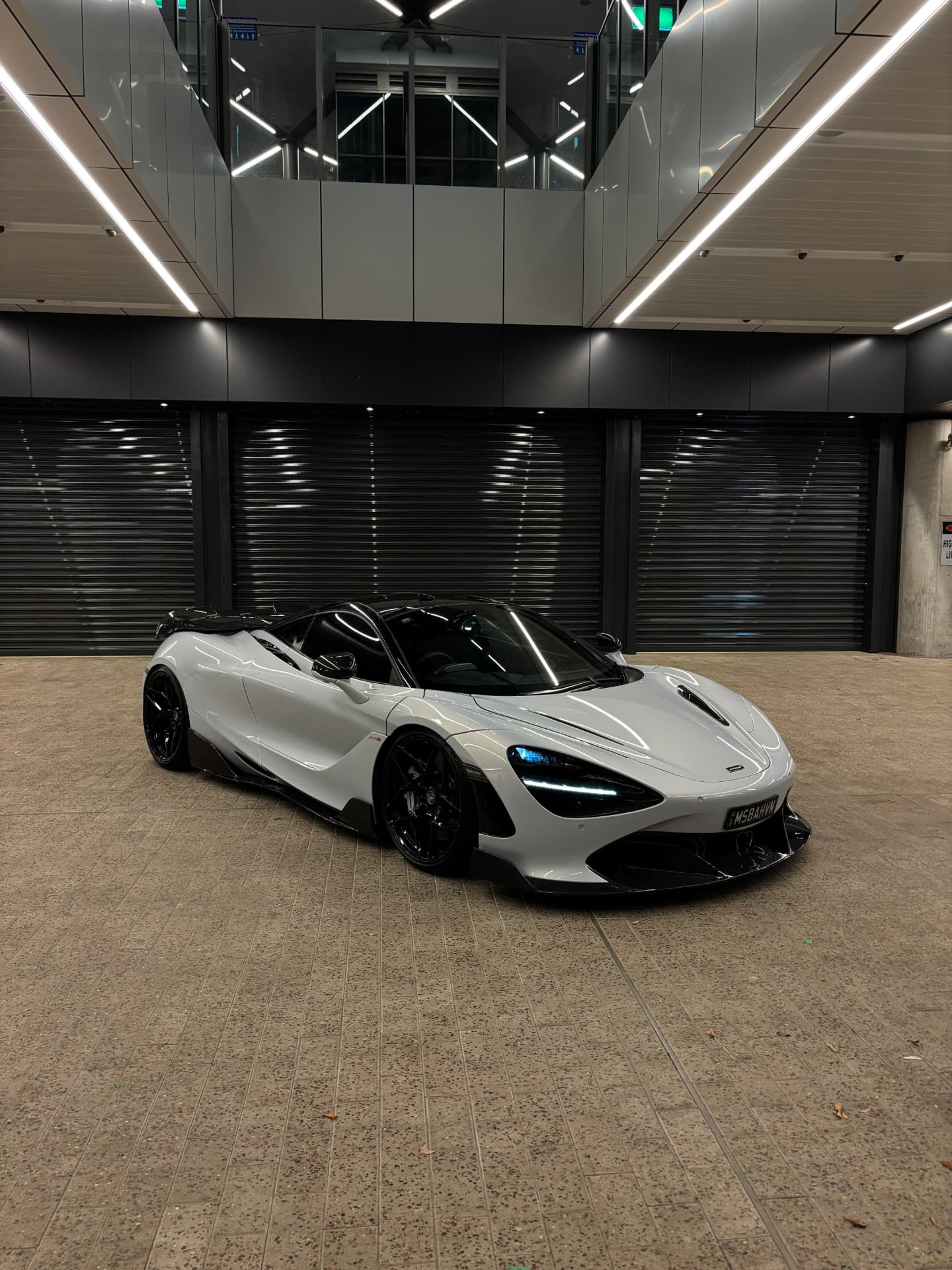 Grey McLaren 720S under linear lighting in a plaza