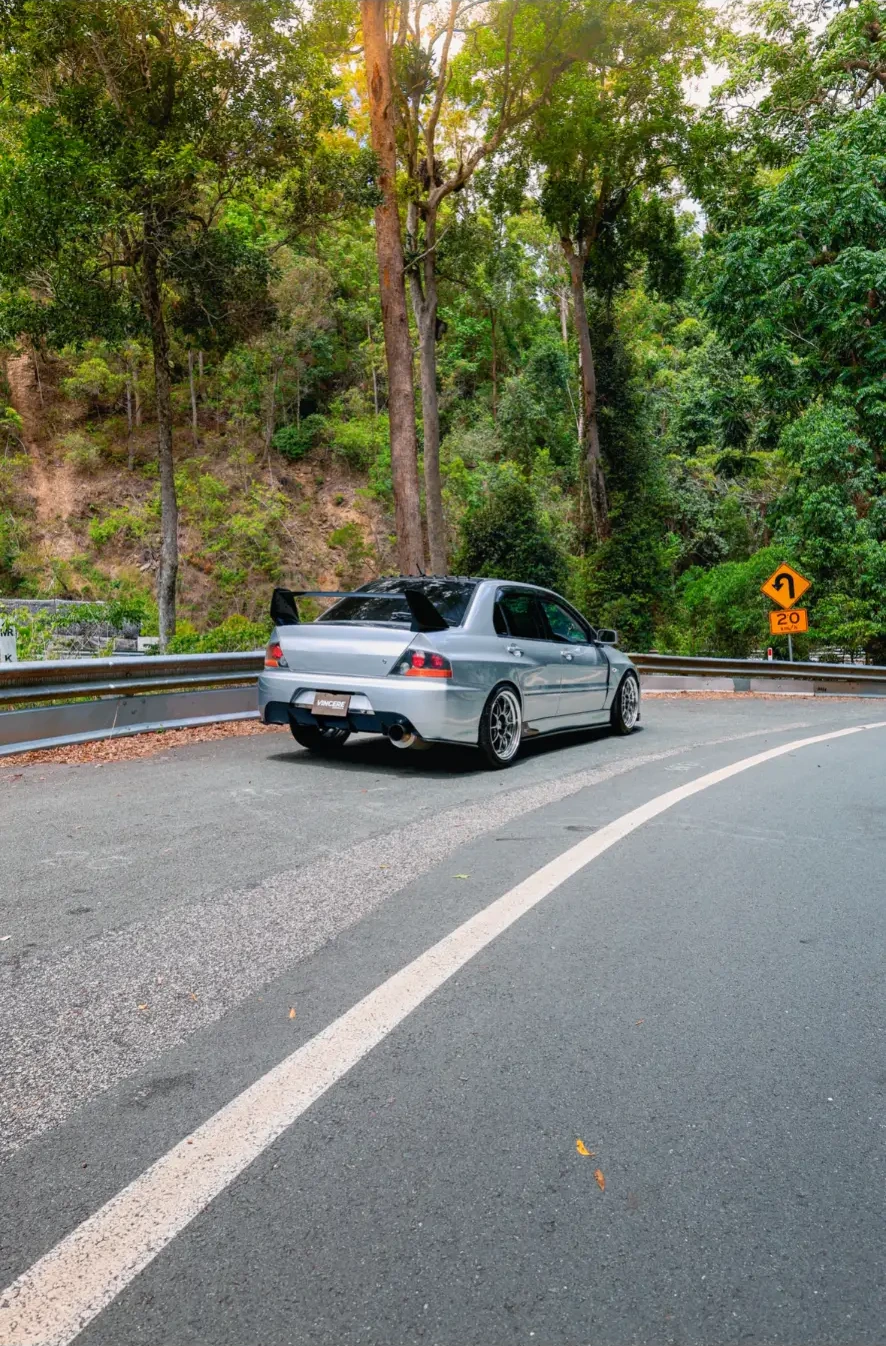 Silver Mitsubishi Evo IX on a rainforest mountain road