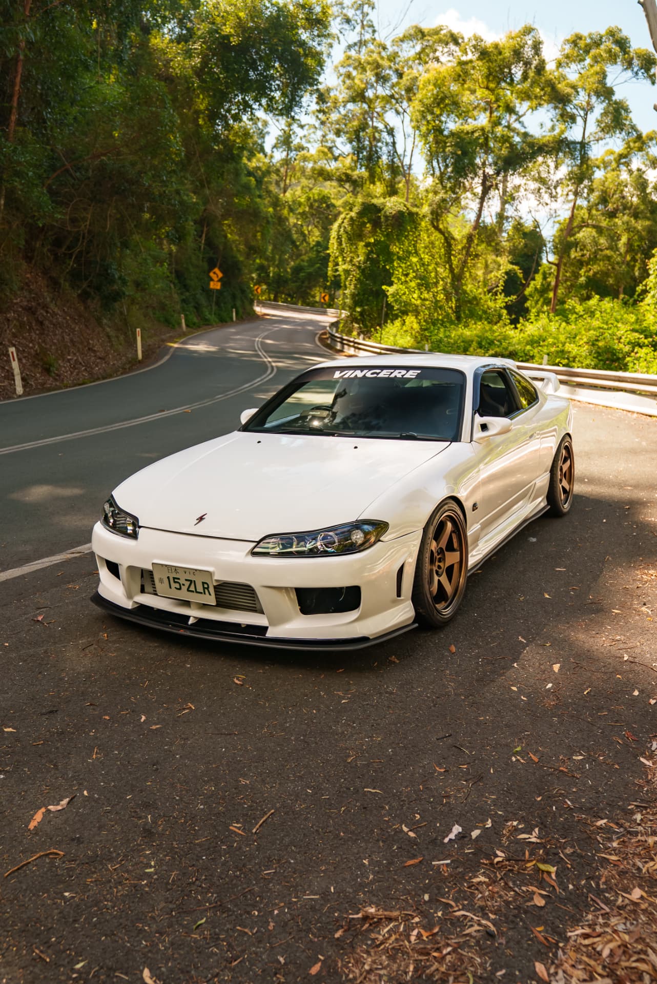 White Nissan Silvia S15 on a winding rainforest hill road