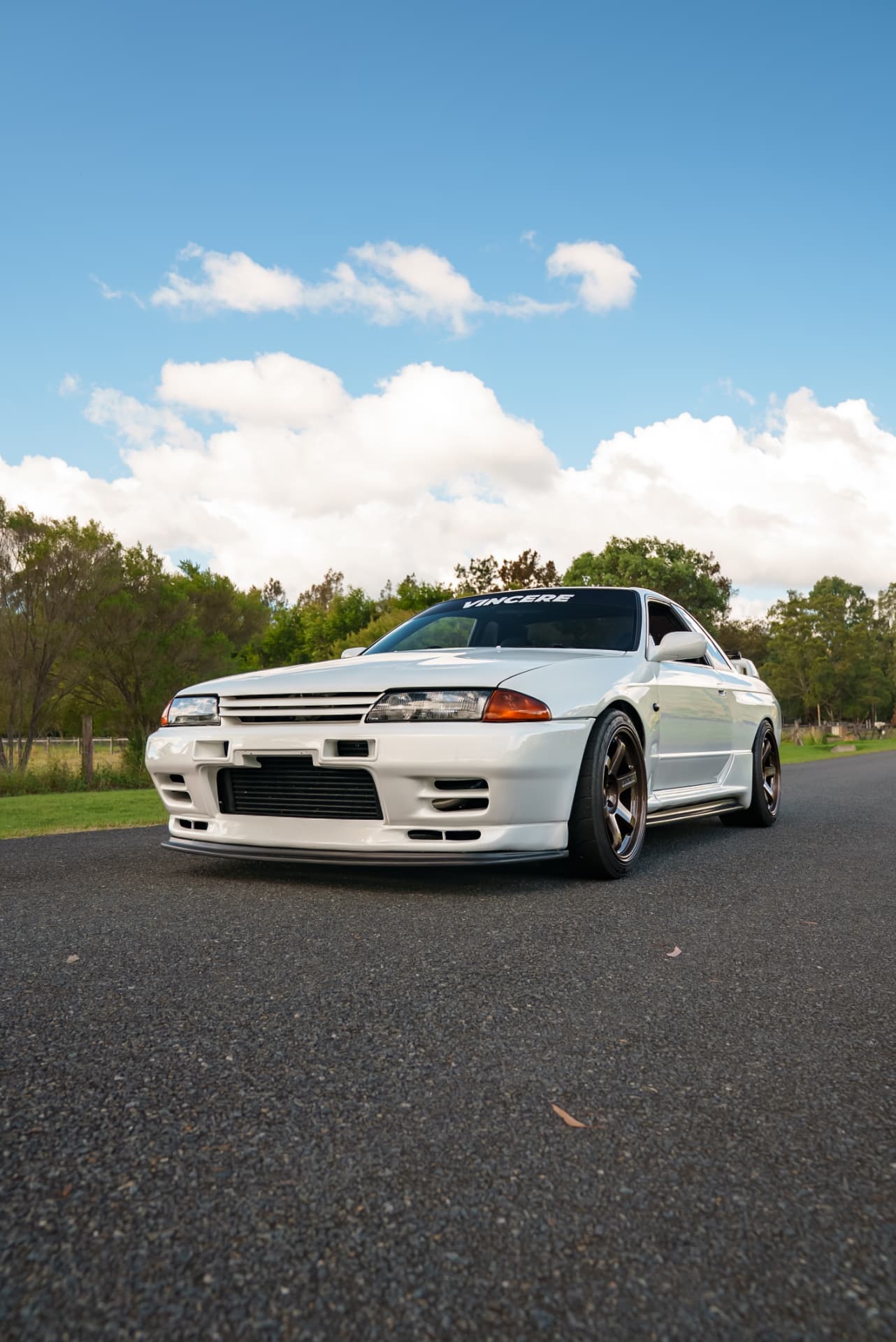 White Nissan Skyline R32 GT-R under a cloud-filled sky