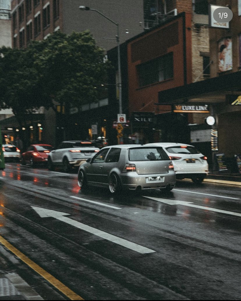 Silver Volkswagen Golf on a wet city street in the rain
