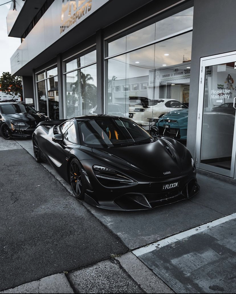 Satin black McLaren 720S outside a motorsports showroom