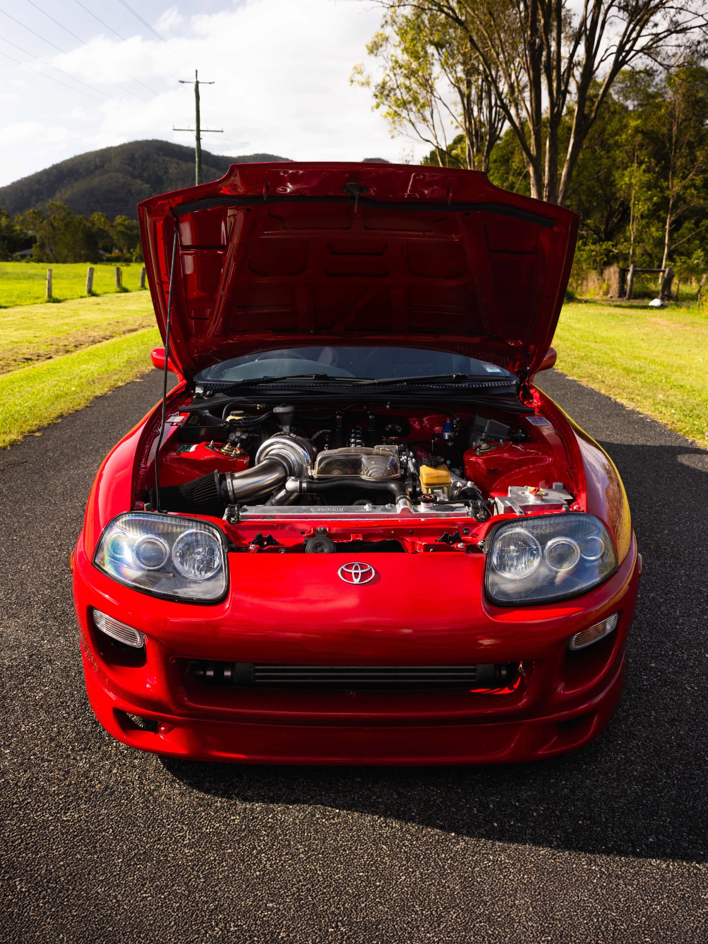 Engine bay of a red Toyota Supra MK4 with the bonnet open