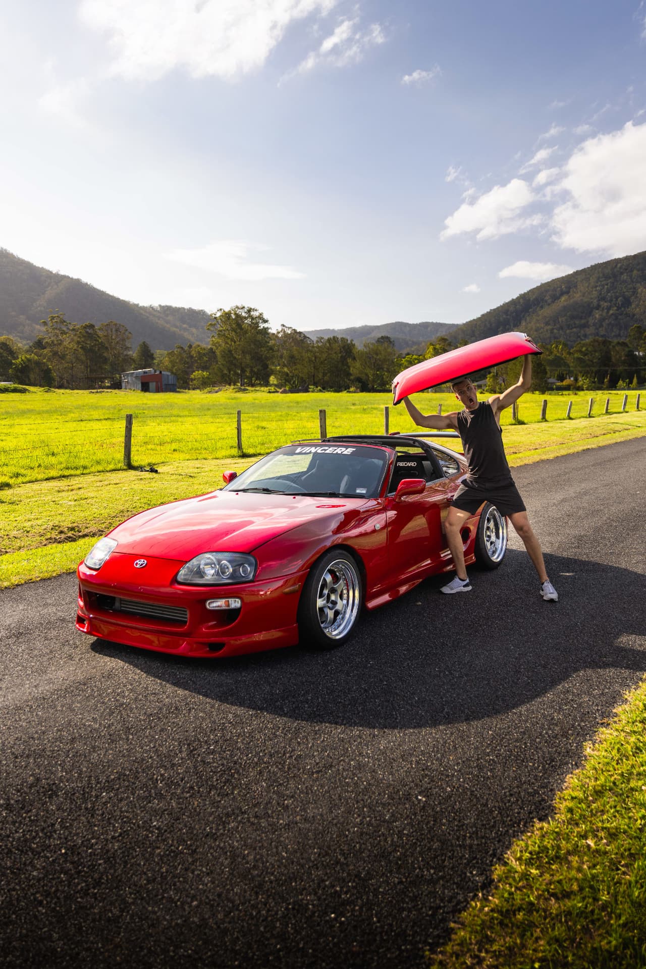Owner lifting the targa roof off a red Toyota Supra MK4