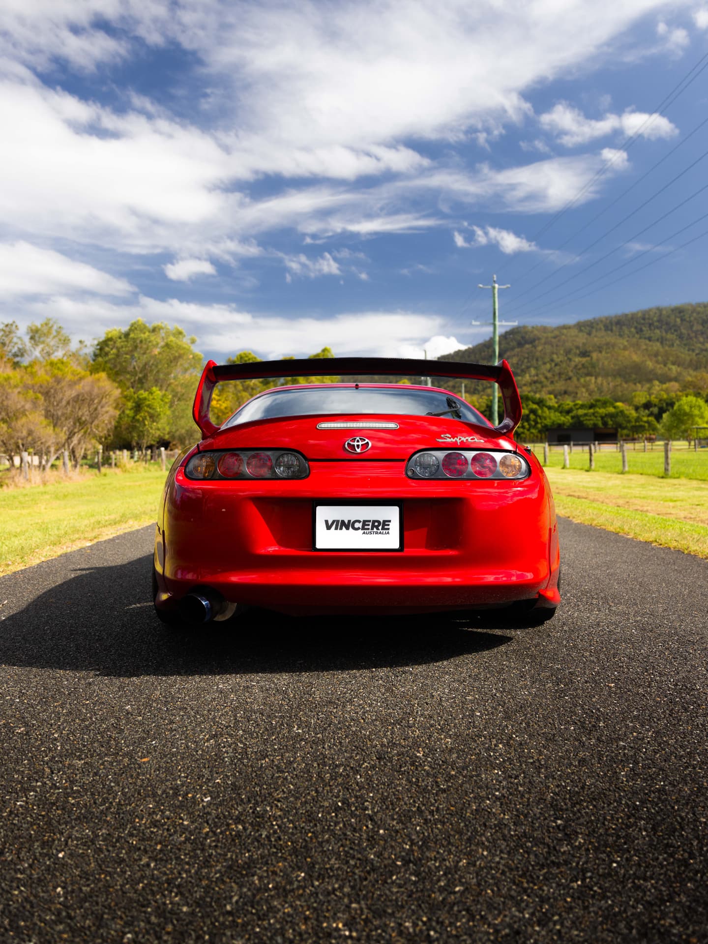Rear view of a red Toyota Supra MK4 with a large wing